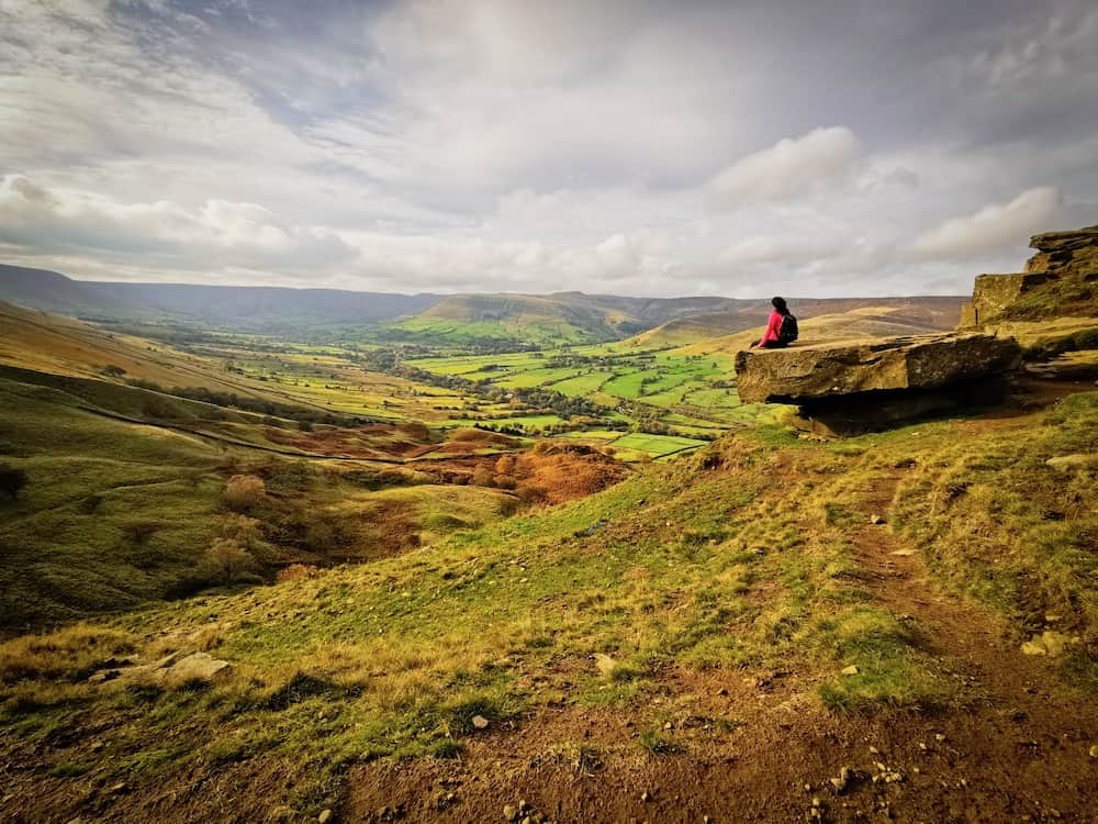 Peak District green fields and person sitting on rock | Peak District Day trip from London by train