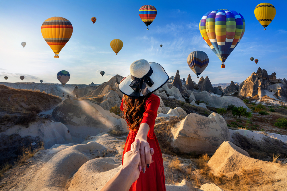 what to wear in Turkey, woman in red dress infront of hot air balloons in Cappadocia