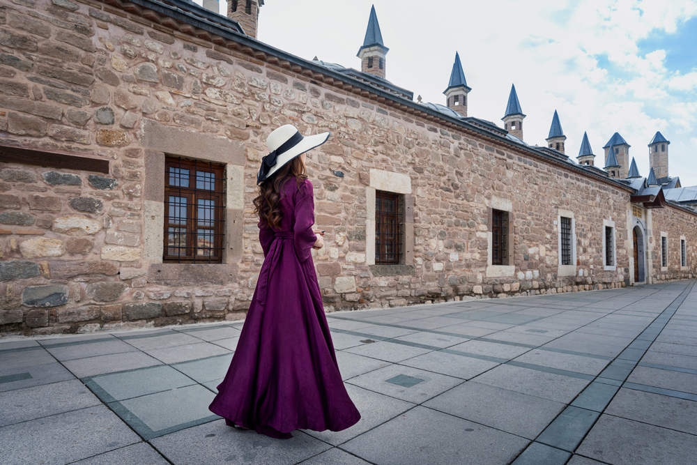 what to wear in Turkey, woman in long purple dress outside mosque in Konya