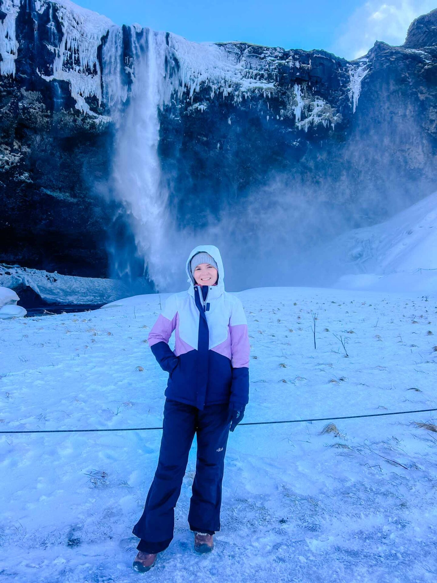 The Wandering Quinn Travel Blog what to wear in Iceland in winter, Ellie wearing ski jacket at iceland waterfall