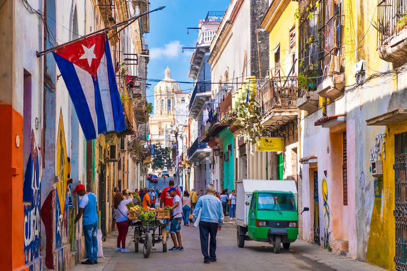 Best countries to visit in August, Street scene with cuban flag on a colorful street in Old Havana