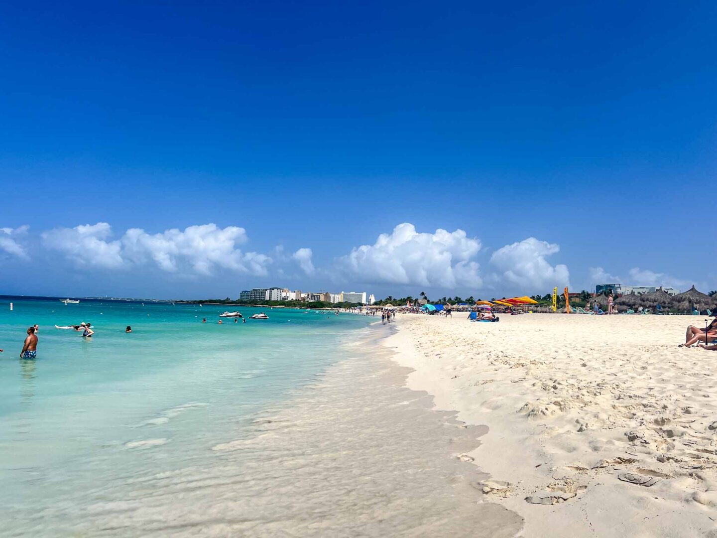 Best countries to visit in August, beach with white sand and blue water and sky in Aruba