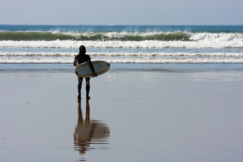 things to do in County Clare, man with surf board at Lahinch Beach