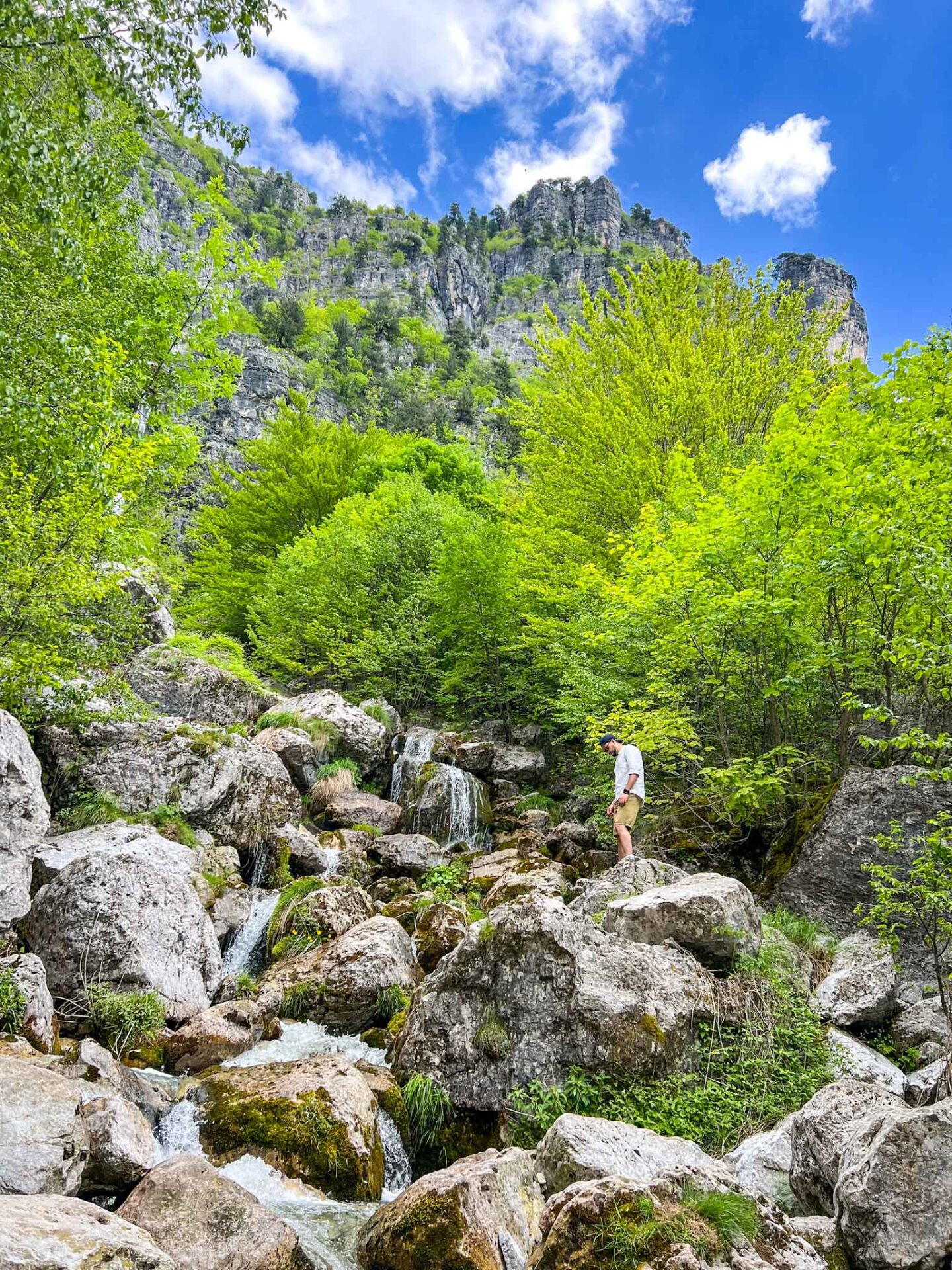 The Wandering Quinn Travel Blog one day in Theth Albania,  man standing at Theth Waterfall