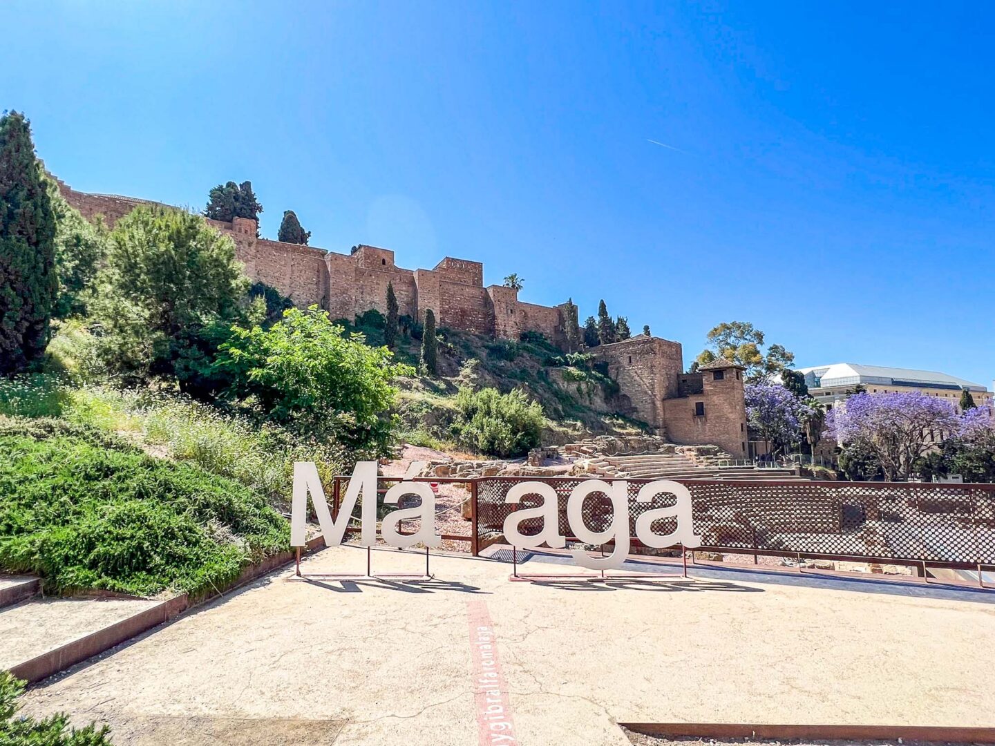 Malaga sign with city fort behind